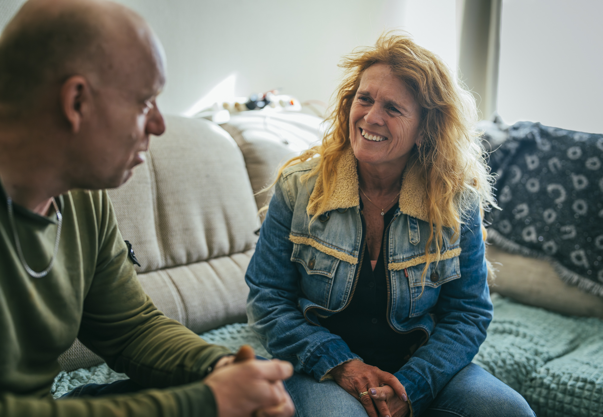 Twee volwassenen op een bank praten met elkaar en kijken vrolijk